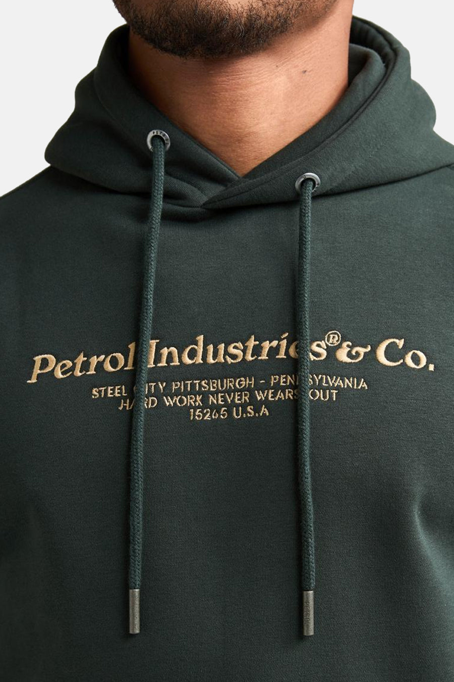 Dark green hooded sweatshirt with gold embroidered logo and drawstrings, front close-up view