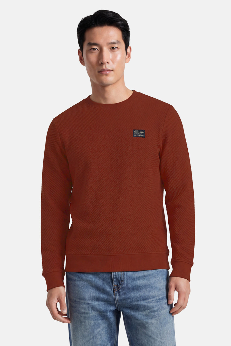 Rouge textured crewneck sweatshirt by Petrol Ind, featuring ribbed cuffs and hem, with small chest patch logo, front view on model wearing blue jeans