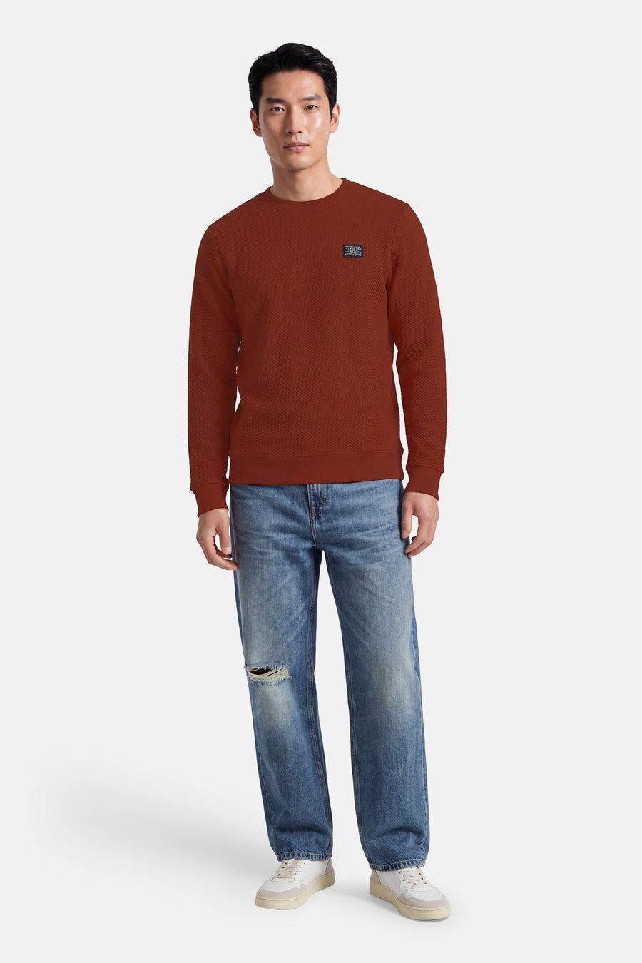 Rouge textured crewneck sweatshirt with ribbed cuffs and small chest patch, worn with distressed jeans and white sneakers, front view