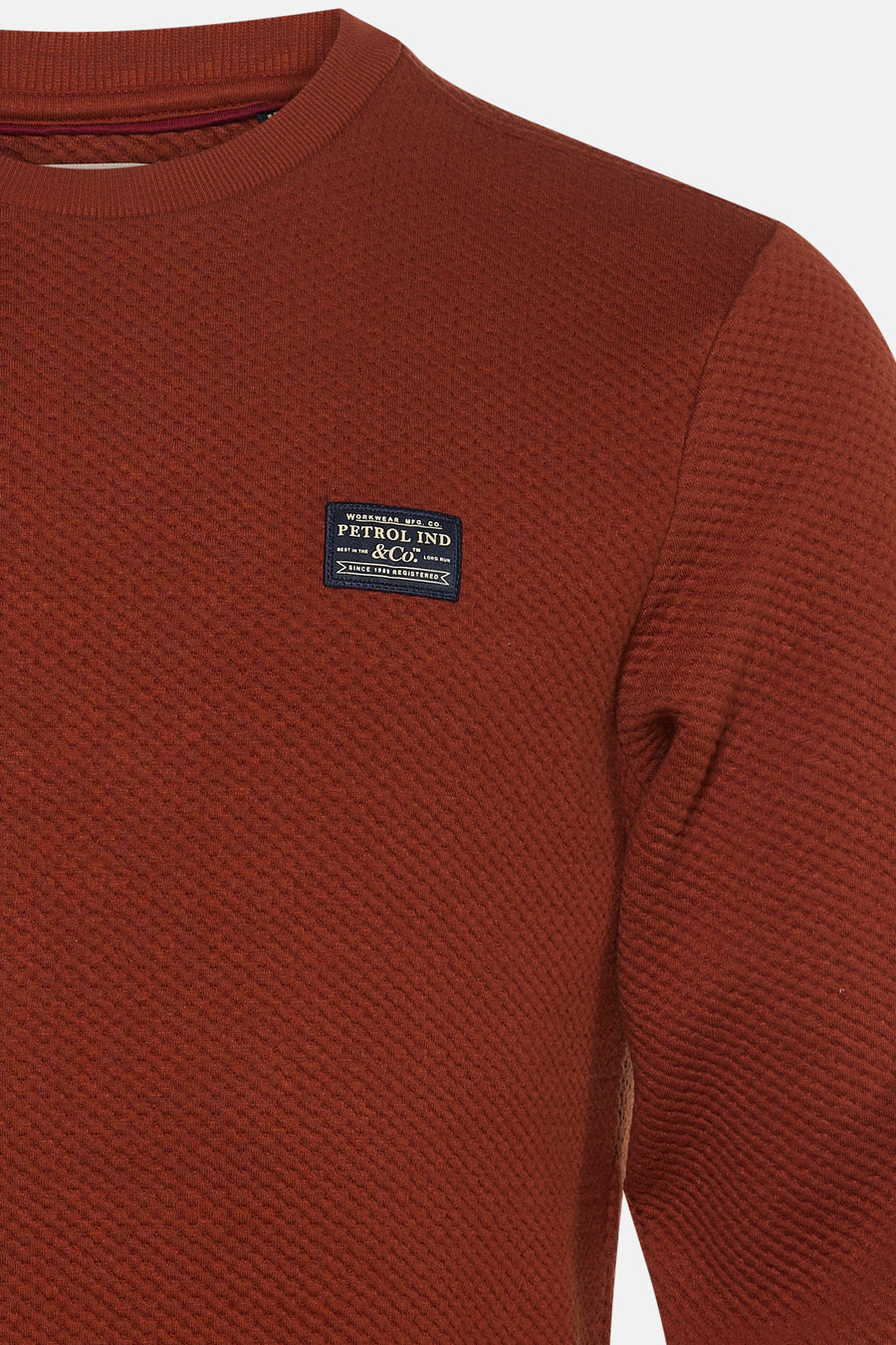 Rust red textured crewneck sweatshirt by Petrol Ind & Co, featuring ribbed neckline and chest patch label, close-up front view