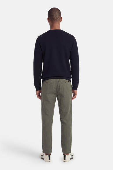 Navy blue textured crewneck sweatshirt back view with ribbed cuffs and hem, worn with olive chinos and white sneakers