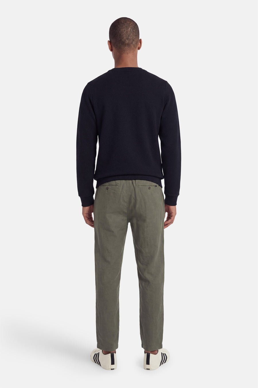 Navy blue textured crewneck sweatshirt back view with ribbed cuffs and hem, worn with olive chinos and white sneakers