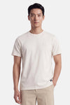 Ecru short-sleeve t-shirt with round neckline and small chest logo, worn by model in front view, paired with beige trousers