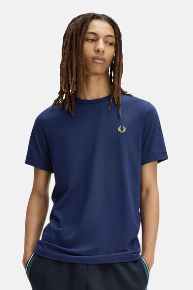 T-shirt bleu marine de FRED PERRY avec logo couronne de laurier doré sur la poitrine gauche, porté par un homme.