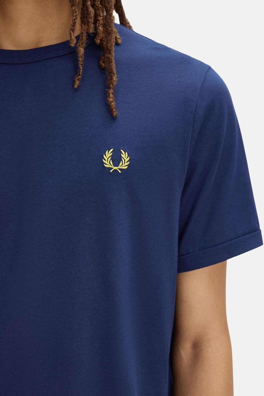 Blauwe T-shirt van FRED PERRY met gouden laurierlogo op de borst en opgerolde korte mouwen.
