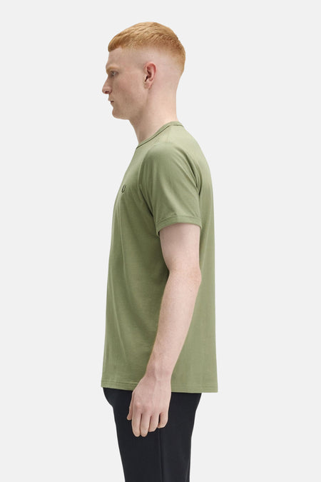 Olijfgroen T-shirt met korte mouwen van FRED PERRY, met klassieke pasvorm en gedragen met een zwarte broek.
