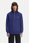 Blauwe coltrui van FRED PERRY met geribde manchetten met strepen en zichtbare zwarte broek.