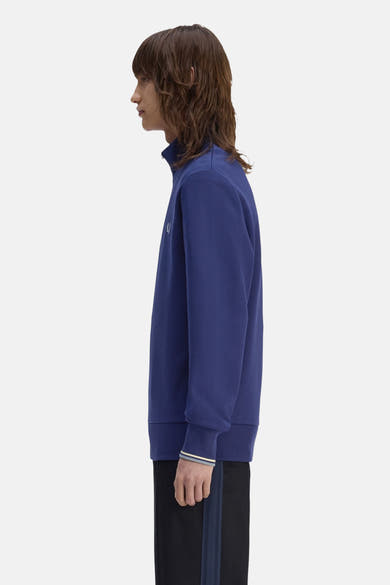 Blauwe coltrui van FRED PERRY, lange mouwen met gestreepte boorden, gedragen met een zwarte gestreepte broek.