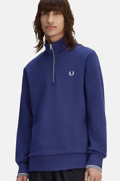 Sweat col roulé bleu par Fred Perry, avec fermeture éclair partielle argentée et logo brodé.