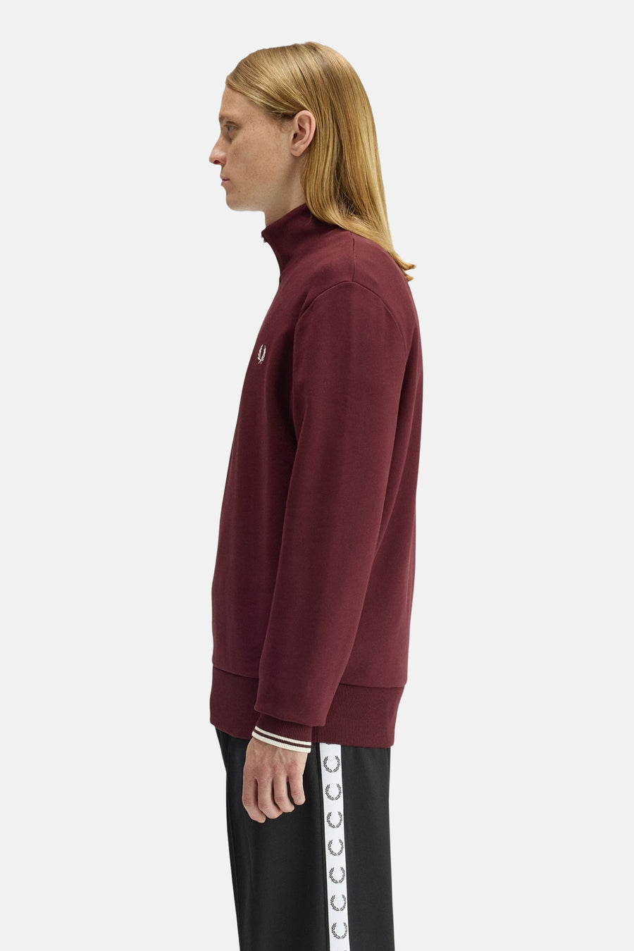 Burgundy high-neck sweatshirt by Fred Perry, side view, featuring small embroidered logo on chest and ribbed cuffs with white stripe trim.