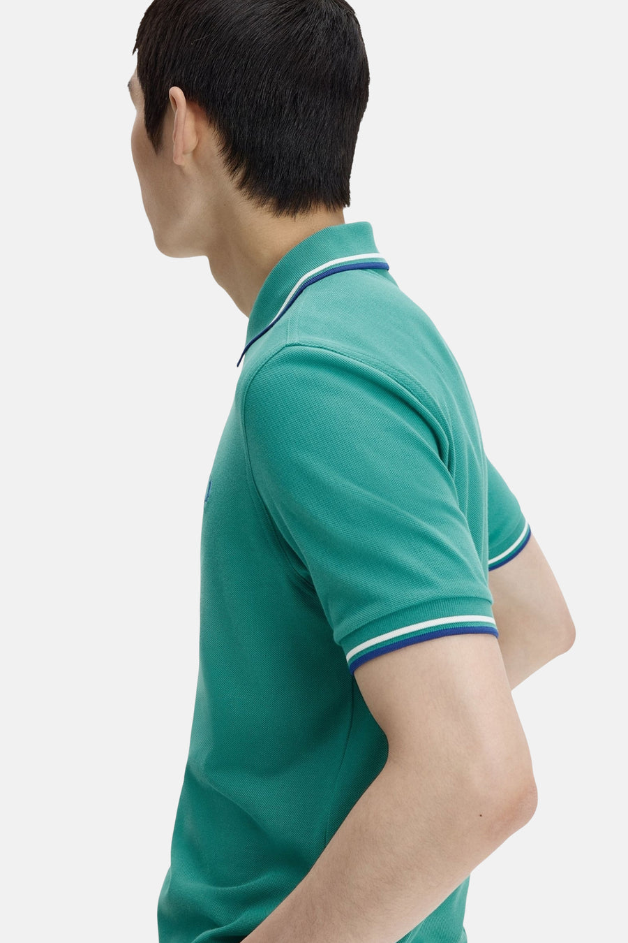 Polo à manches courtes vert de FRED PERRY, avec col et manches à bordure contrastée, en vue de côté.
