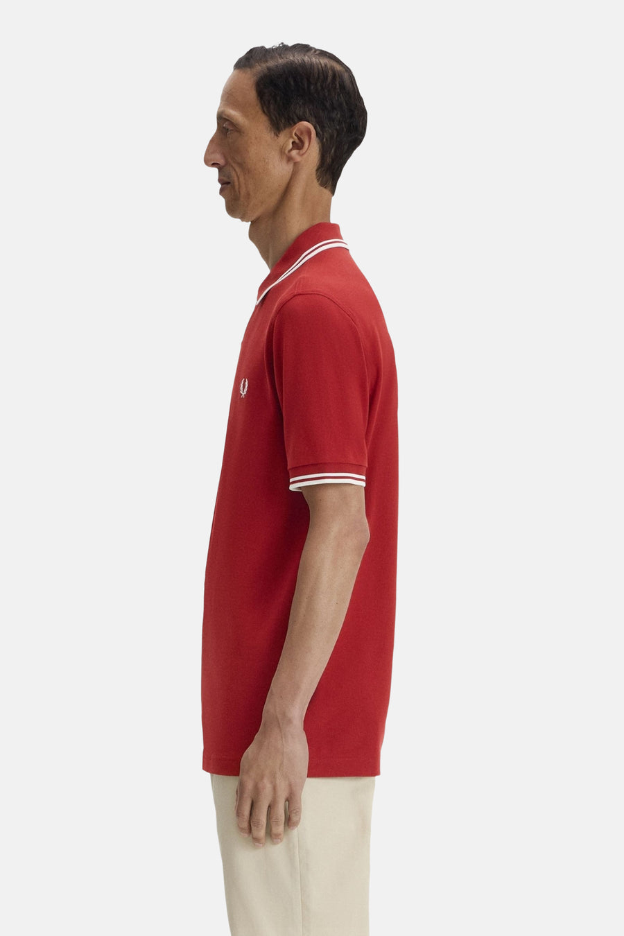 Rood poloshirt met korte mouwen van Fred Perry, met witte gestreepte kraag en mouwboorden, zijaanzicht.