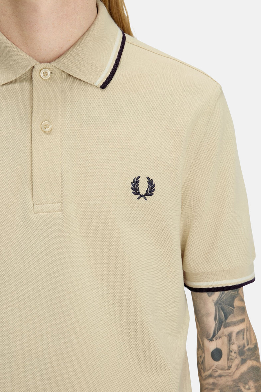 Beige poloshirt met korte mouwen van Fred Perry, met contrasterende bies op de kraag en mouwen.