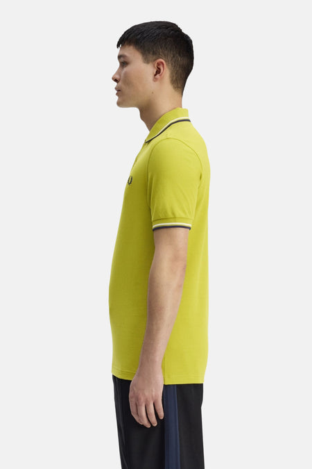 Groen poloshirt van Fred Perry, met contrasterende gestreepte kraag en mouwen, zijaanzicht.
