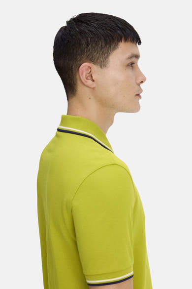 Polo vert par FRED PERRY, coupe classique avec rayures contrastantes au col et aux manches, vue de côté.
