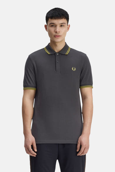 Grijze Fred Perry polo met korte mouwen, versierd met een geborduurd logo en gestreepte afwerkingen aan de kraag en mouwen.
