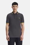 Grijze Fred Perry polo met korte mouwen, versierd met een geborduurd logo en gestreepte afwerkingen aan de kraag en mouwen.