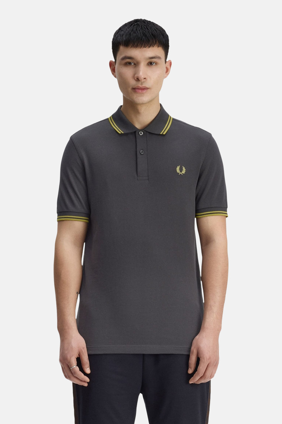 Grijze Fred Perry polo met korte mouwen, versierd met een geborduurd logo en gestreepte afwerkingen aan de kraag en mouwen.