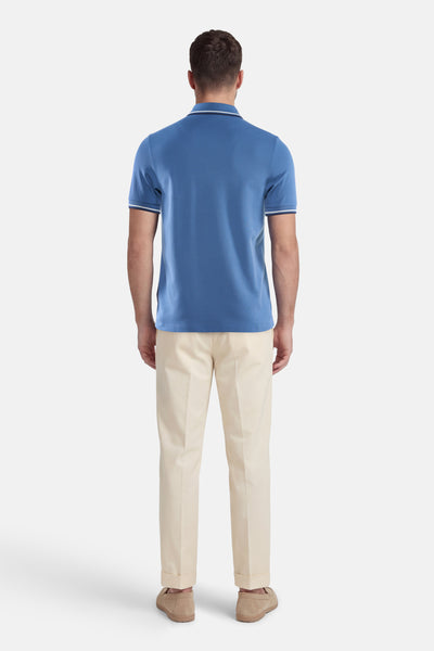 Marineblauwe polo met witte bies van FRED PERRY, gedragen met een beige broek en suède loafers.