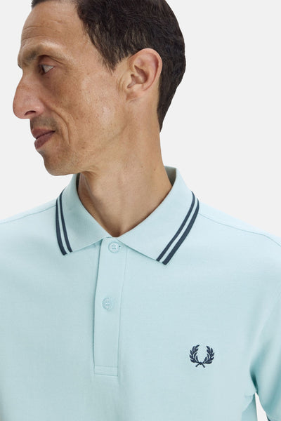 Blauwe polo met korte mouwen van FRED PERRY, met marineblauwe strepen op de kraag en geborduurd logo.