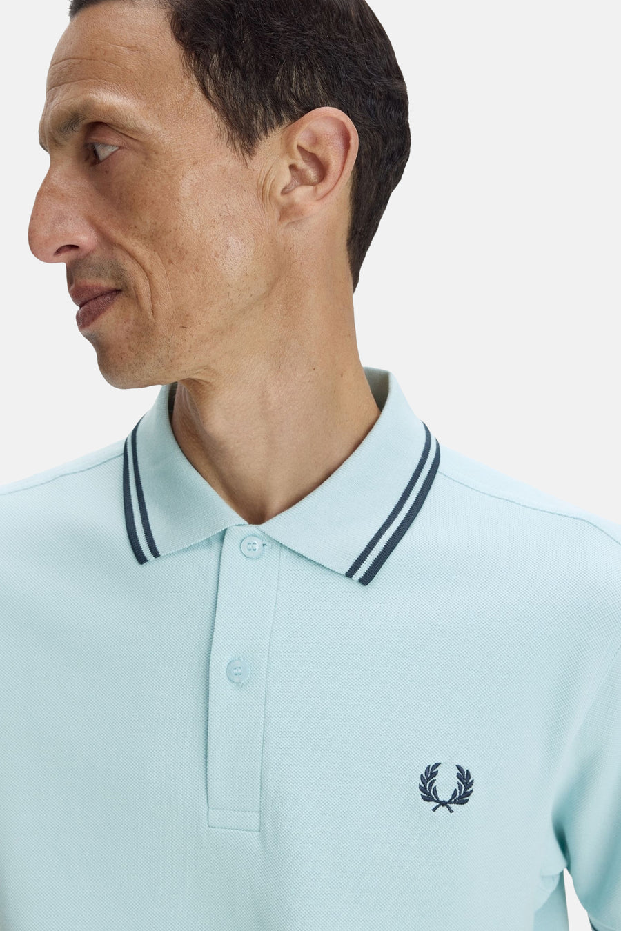 Polo à manches courtes bleu de FRED PERRY, avec rayures marine au col et logo brodé.
