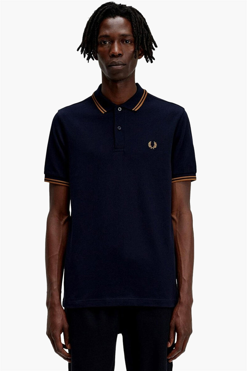 Navy blue pique polo shirt with gold trim collar and cuffs, featuring embroidered laurel wreath logo on chest, front view.
