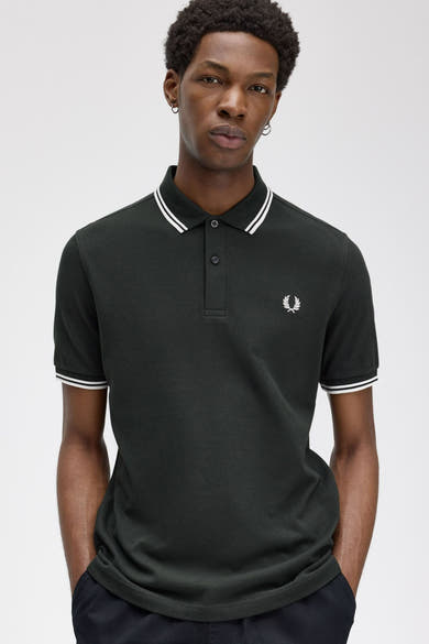 Polo vert foncé à manches courtes par Fred Perry, avec double rayure blanche au col et aux manches.