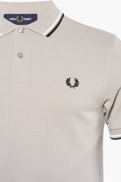 Grey pique polo shirt by Fred Perry with black embroidered laurel wreath logo and striped collar trim, front close-up view
