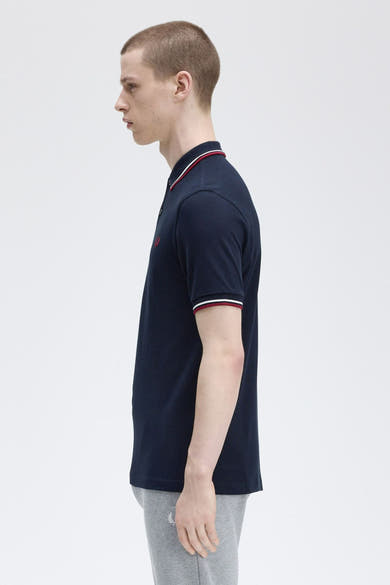Polo bleu marine à manches courtes de Fred Perry avec bordure rayée au col et aux manches.