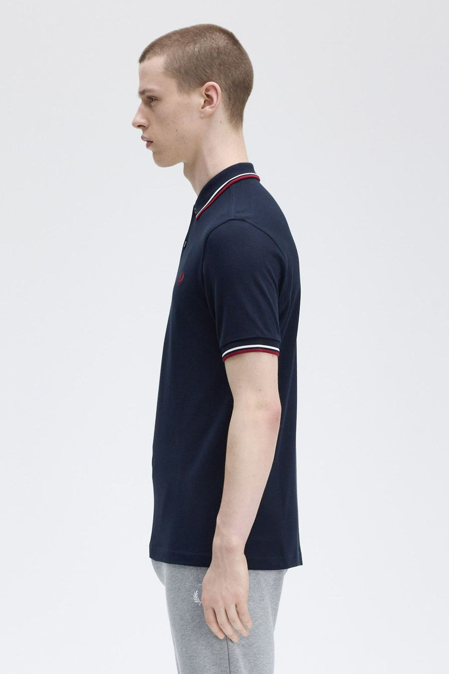 Polo bleu marine à manches courtes de Fred Perry avec bordure rayée au col et aux manches.