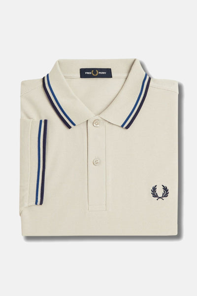 Polo beige en coton de Fred Perry, avec rayures bleu marine et bleu clair au col et manches, logo brodé.