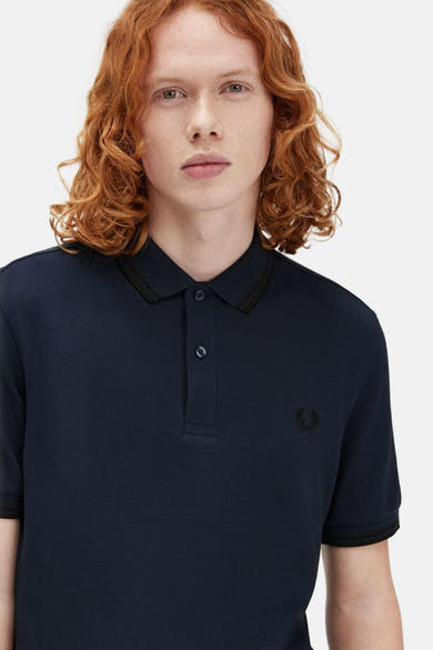 Blauwe korte mouw polo van FRED PERRY, met een collar en gestreepte ribbenmouwen.
