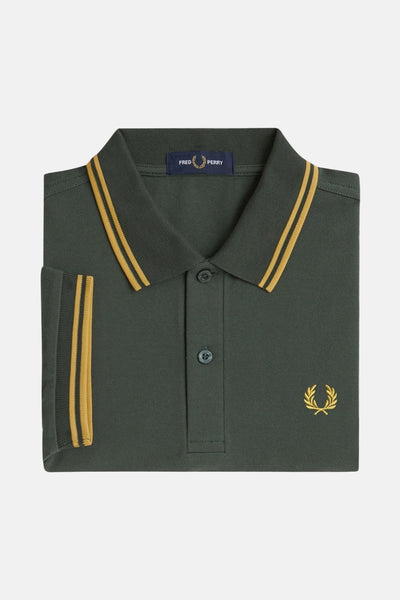 Polo à manches courtes vert, par Fred Perry, avec rayures dorées au col et au bord des manches.