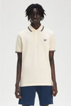 Polo-shirt met FRED PERRY, ecru, met een dubbele marinestreep op het collet en de mouwen, gedragen met een eenvoudig blauw marineshort.