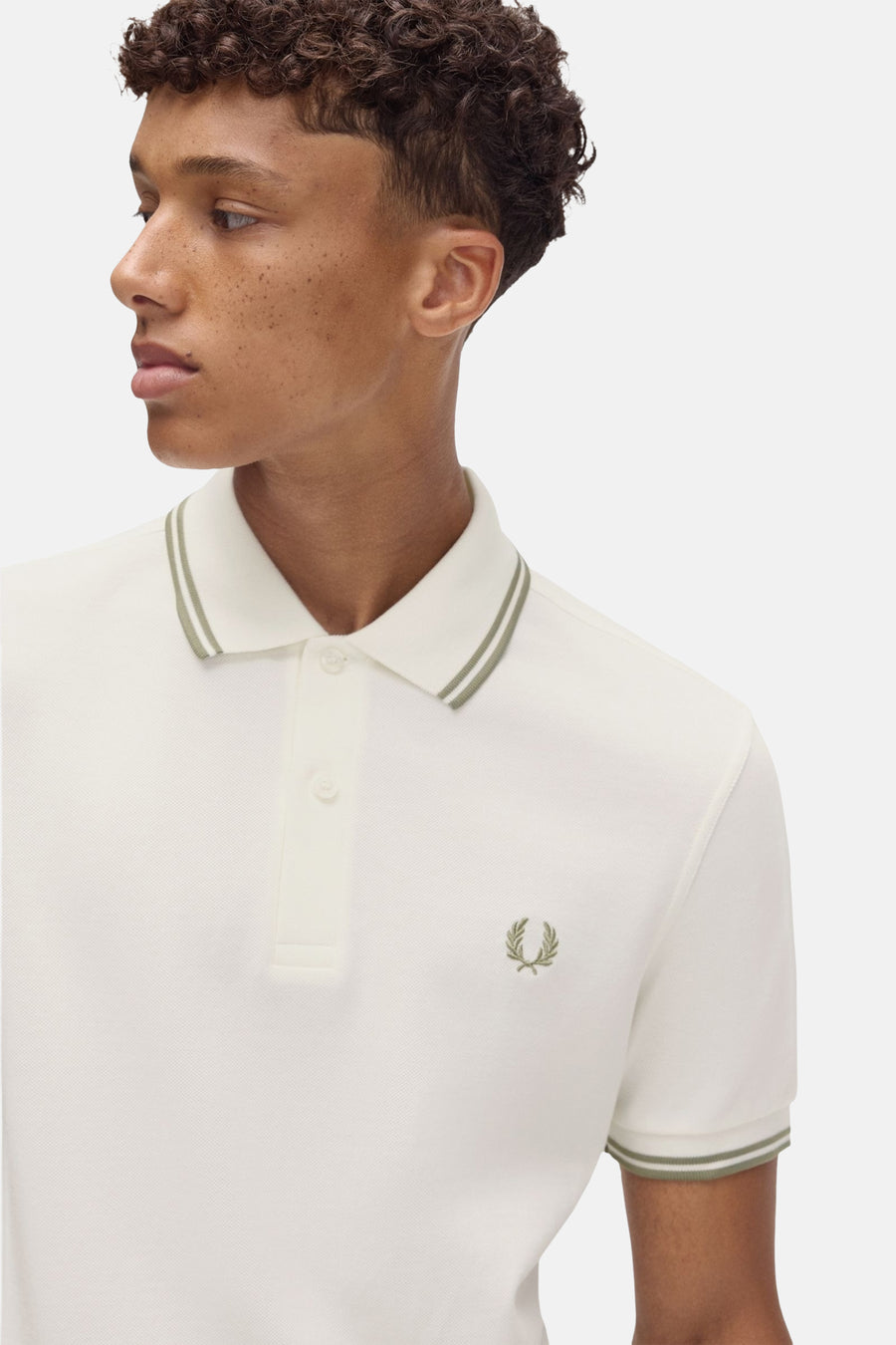 Polo écru à manches courtes de Fred Perry, avec double liseré vert olive au col et aux manches.
