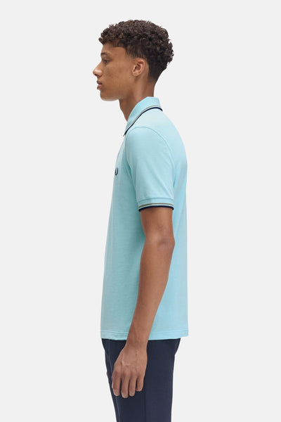 Polo turquoise à manches courtes de Fred Perry, avec col et manches à rayures contrastées.