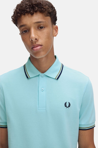 Polo turquoise à manches courtes de Fred Perry, avec liseré au col et aux manches.