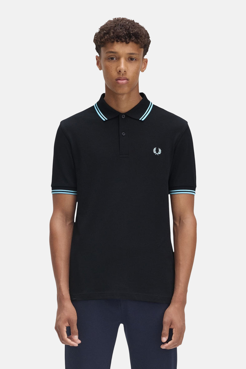 Polo bleu foncé à manches courtes de Fred Perry, avec des rayures bleu clair au col et aux manches.