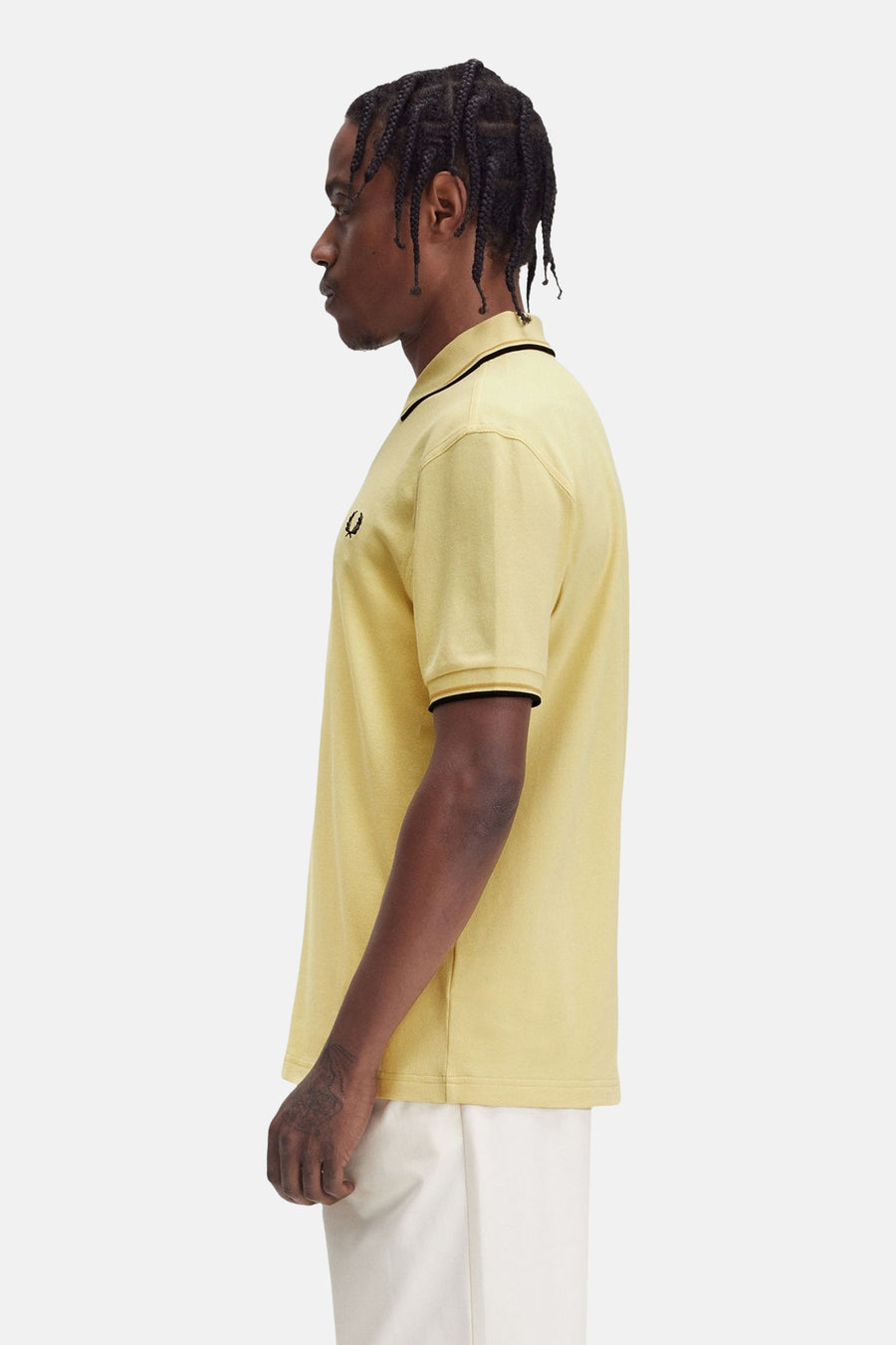 Polo jaune à manches courtes de Fred Perry avec garniture noire au col et aux manches, en vue latérale.