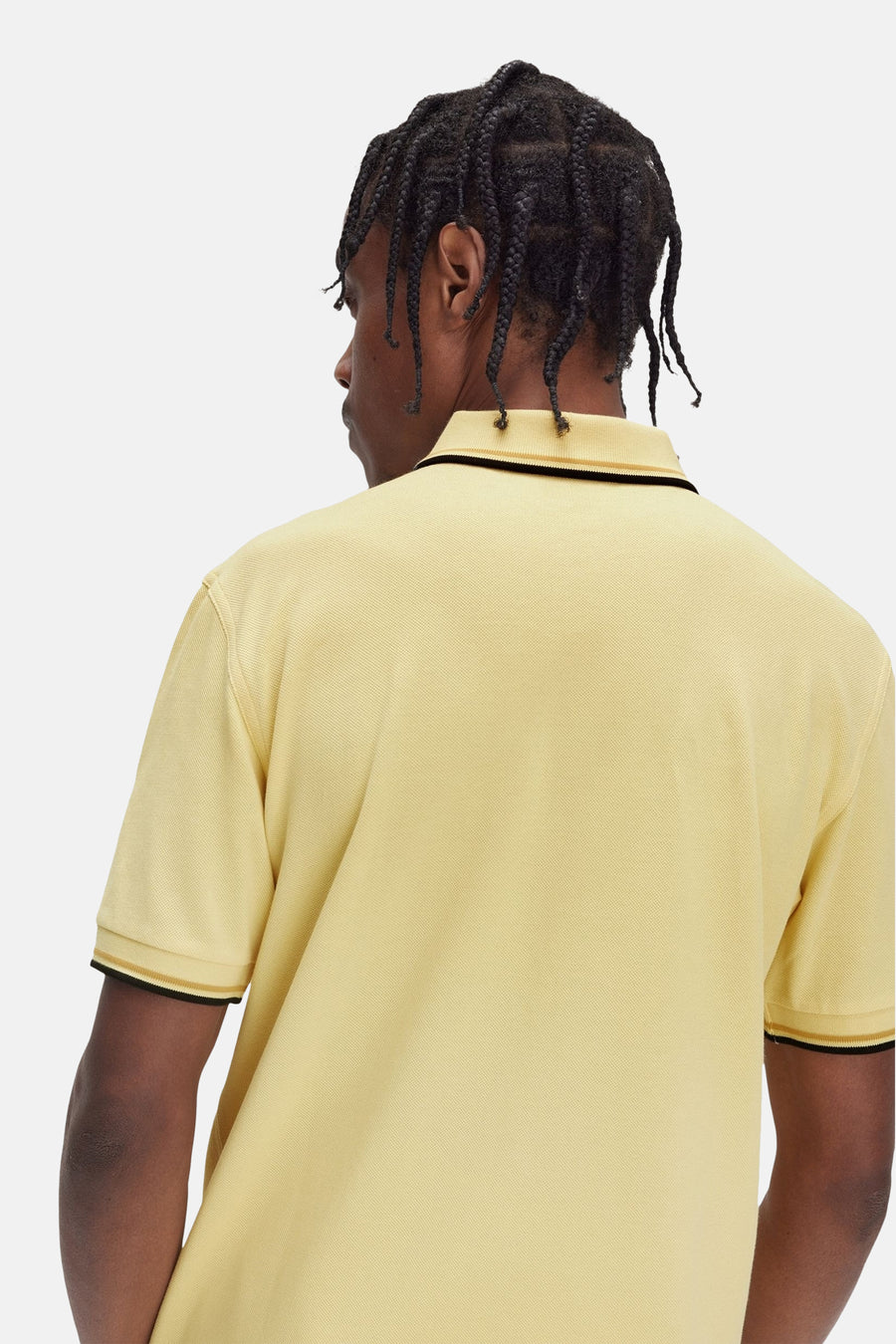 Polo jaune à manches courtes de FRED PERRY, avec bordures noires et dorées au col et aux manches.