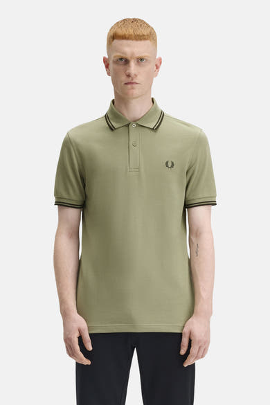 Polo à manches courtes olive de Fred Perry, avec col et manches à rayures noires et logo brodé.
