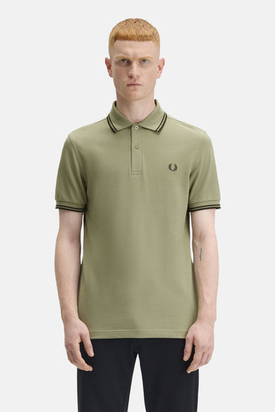 Polo à manches courtes olive de Fred Perry, avec col et manches à rayures noires et logo brodé.
