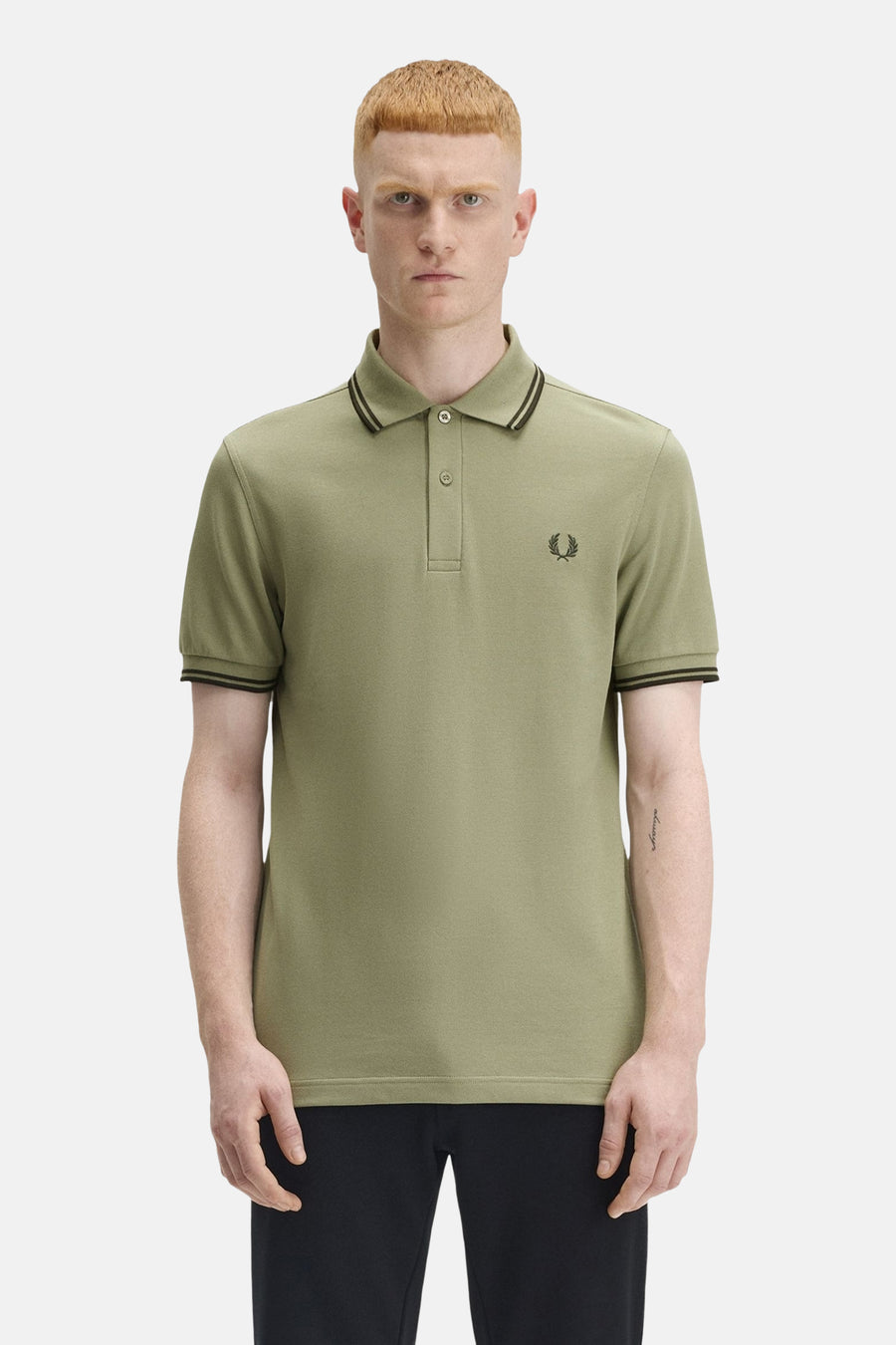 Polo à manches courtes olive de Fred Perry, avec col et manches à rayures noires et logo brodé.
