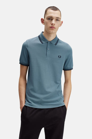 Polo bleu à manches courtes par FRED PERRY, avec rayures contrastées au col et aux manches.