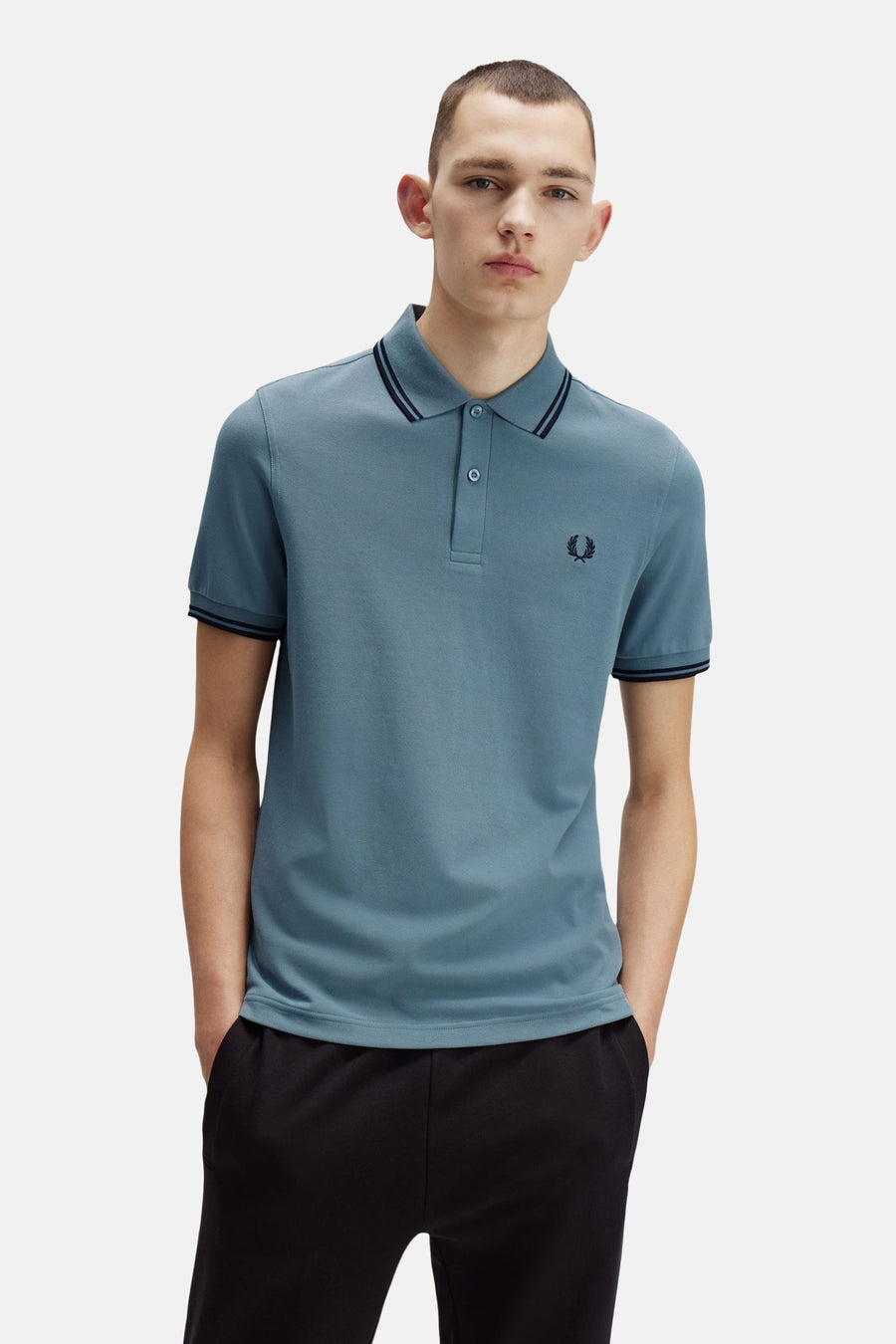 Polo bleu à manches courtes par FRED PERRY, avec rayures contrastées au col et aux manches.
