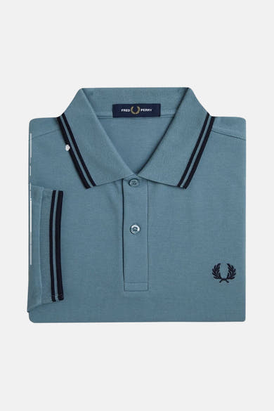 Polo bleu à manches courtes de Fred Perry, avec rayures noires au col et au bord des manches et logo brodé.