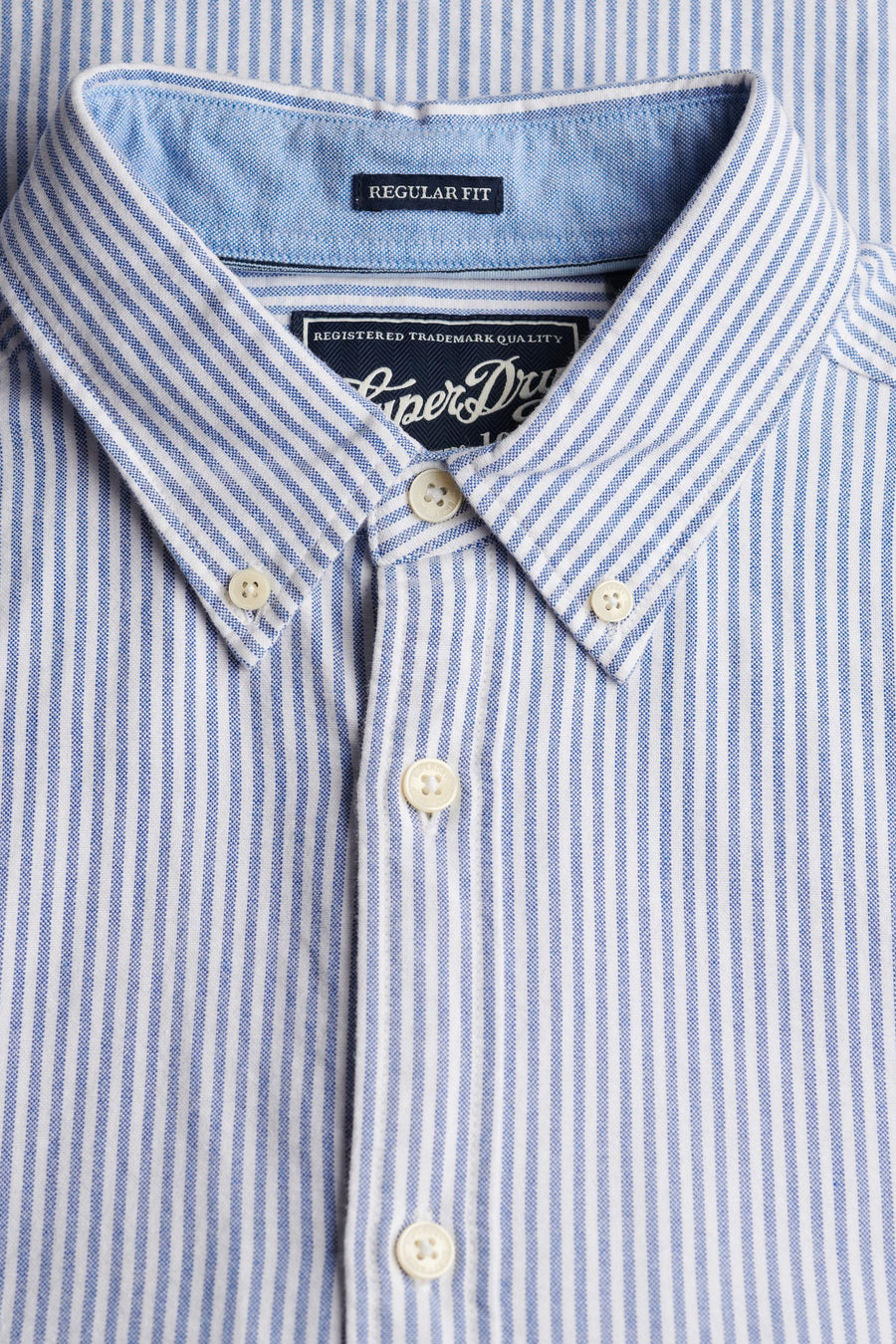 Chemise à manches longues bleue à rayures, de SUPERDRY, avec col boutonné et détails de l'étiquette.