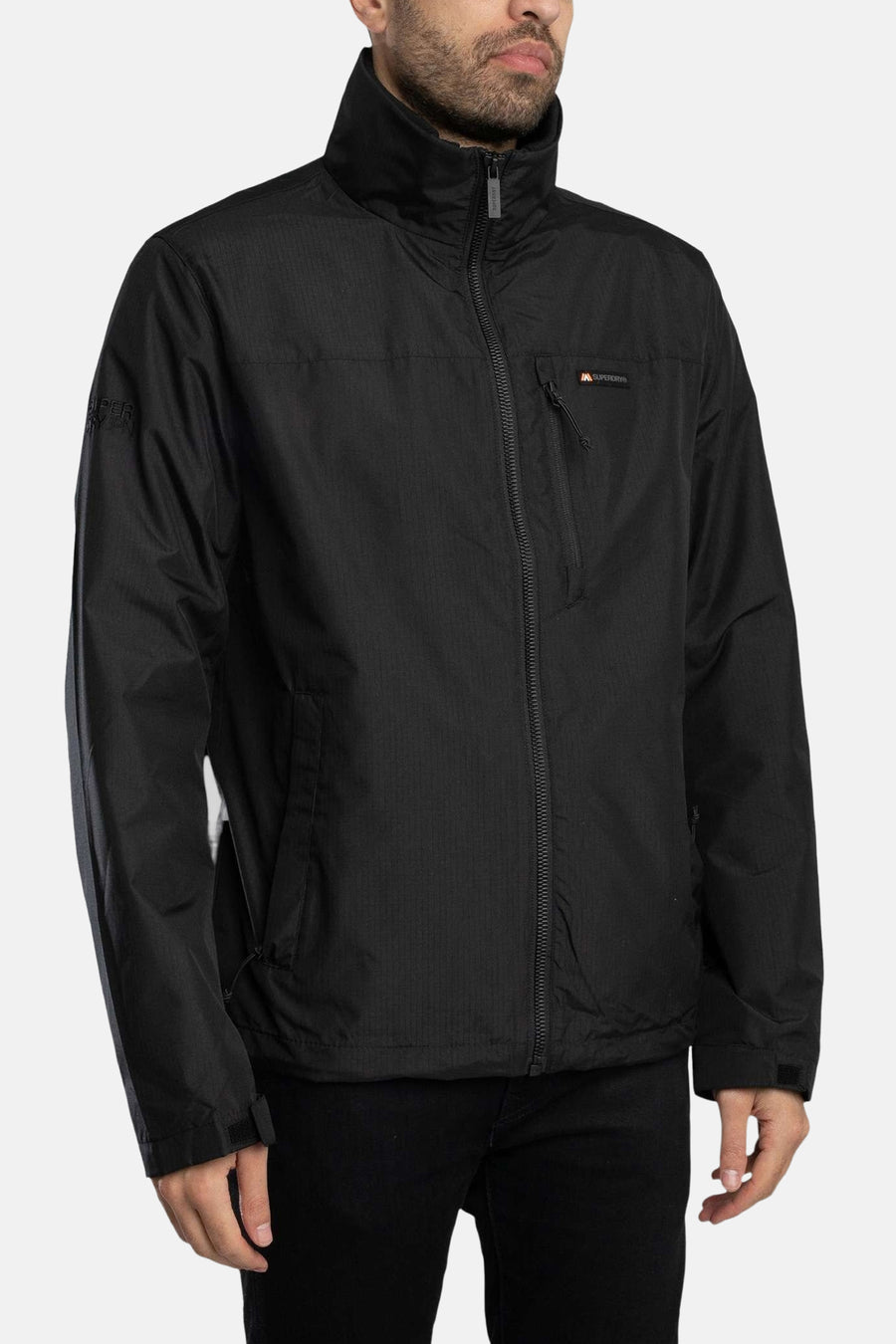 Veste de pluie noire par SUPERDRY, avec fermeture éclair et poches zippées.