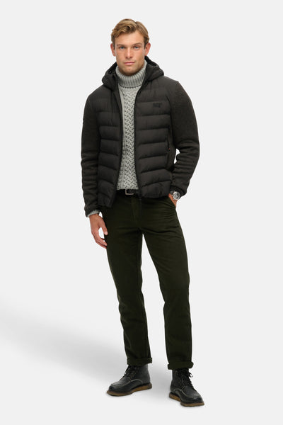 Veste de pluie noire de SUPERDRY avec manches tricotées, pantalon vert olive et bottes en cuir.