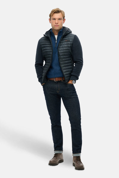 Veste de pluie bleue par SUPERDRY, portée avec un jean foncé et des chaussures de marche marron.